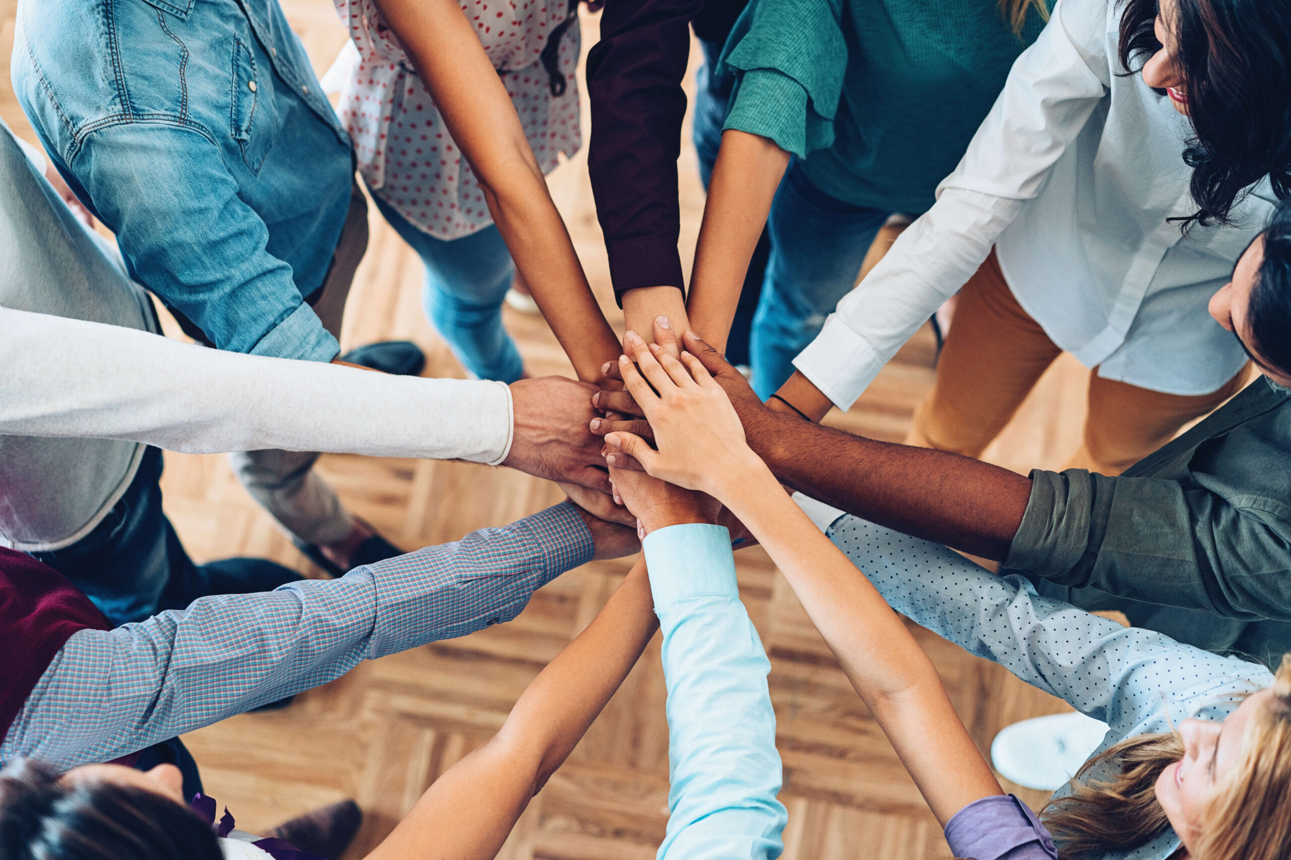 Diverse group of people putting hands in center.