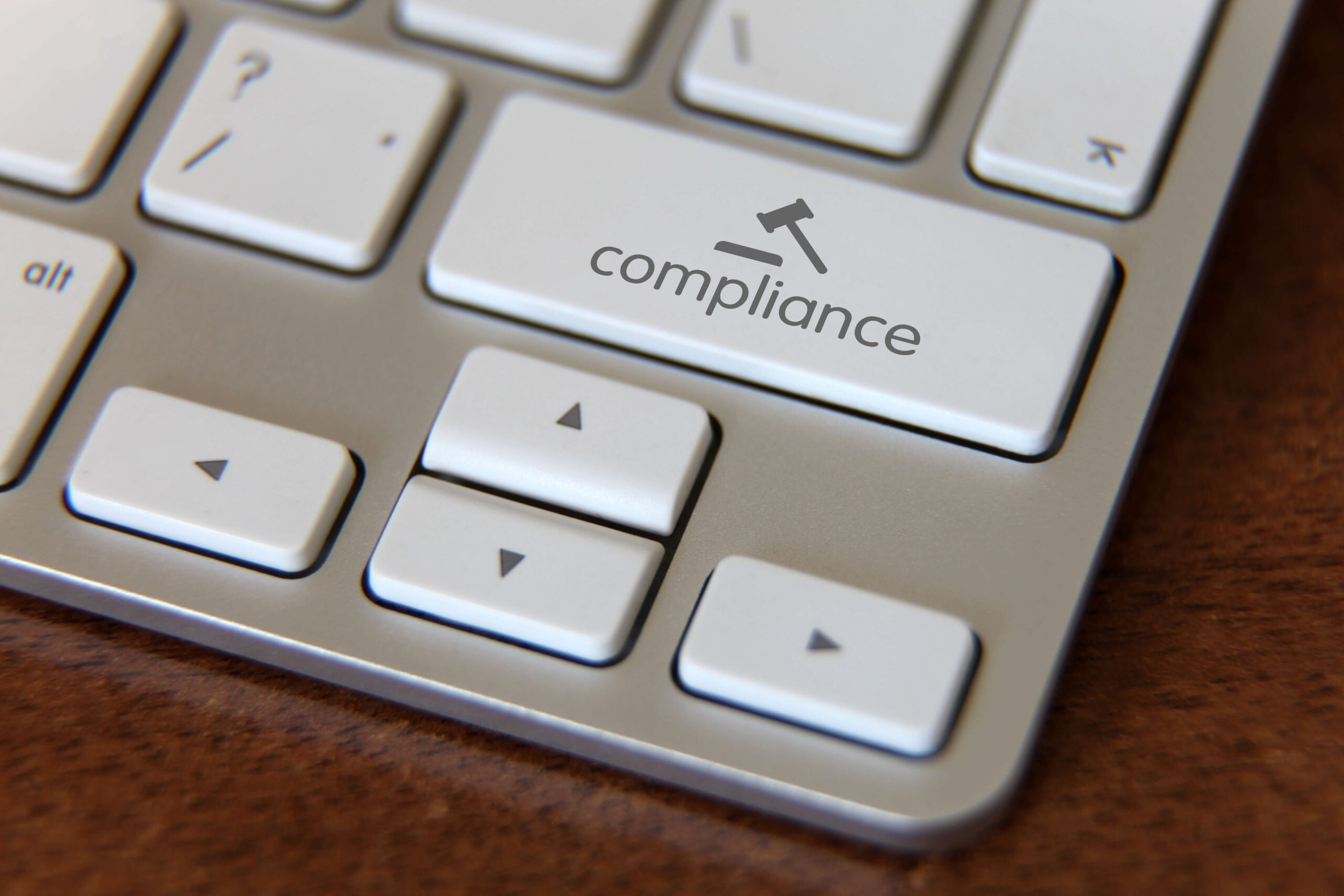 Keyboard with key that says "Compliance" with icon of a gavel.