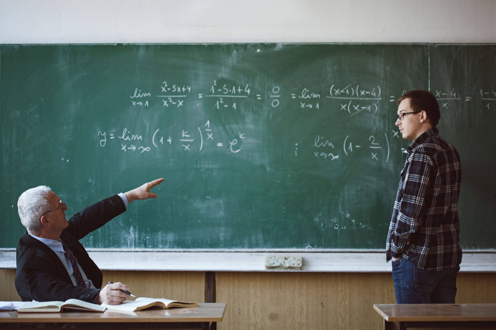 Teacher and student discussing in front of chalkboard.