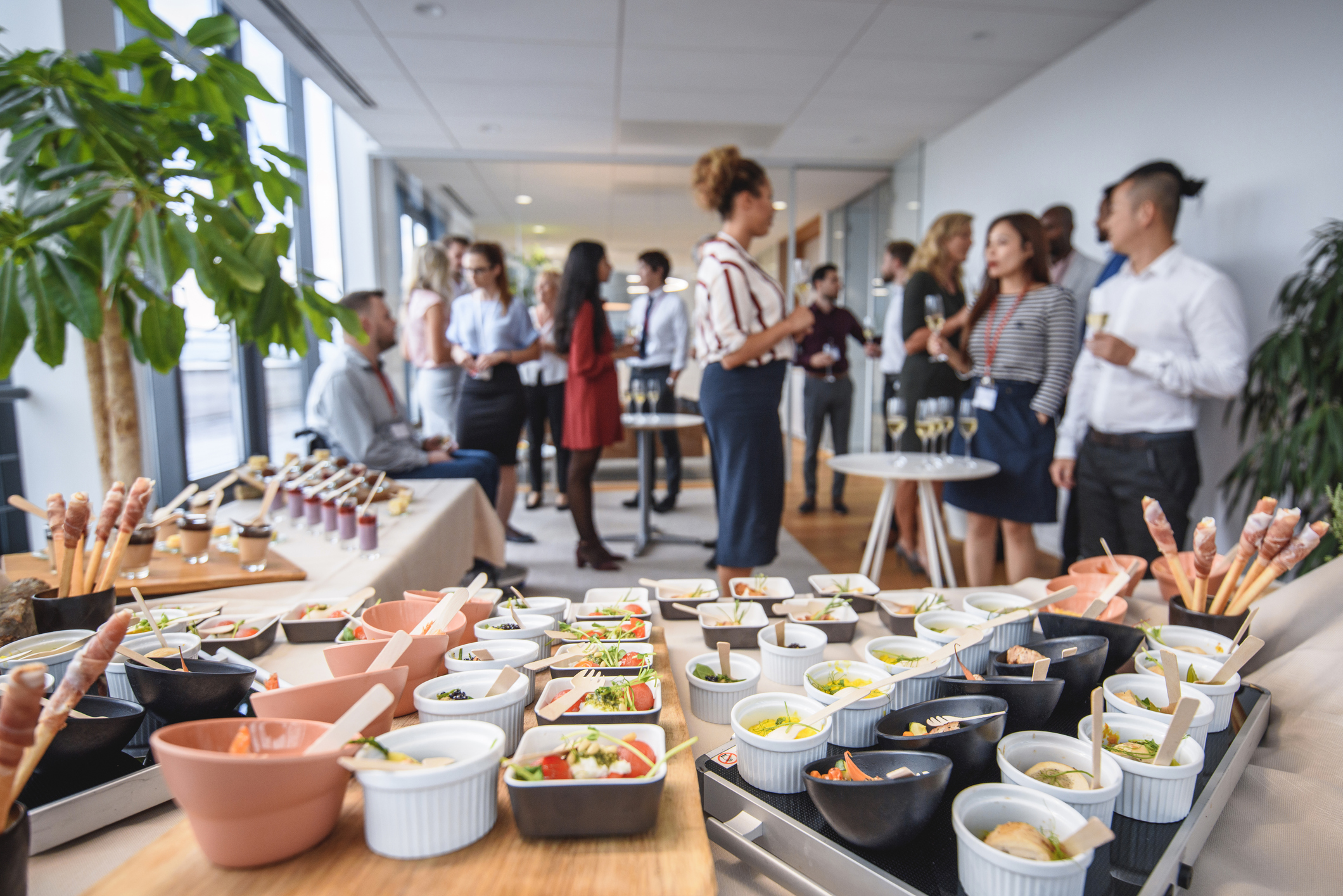 Focus on foreground gourmet small dishes and desserts on buffet tables at new business launch celebration event.