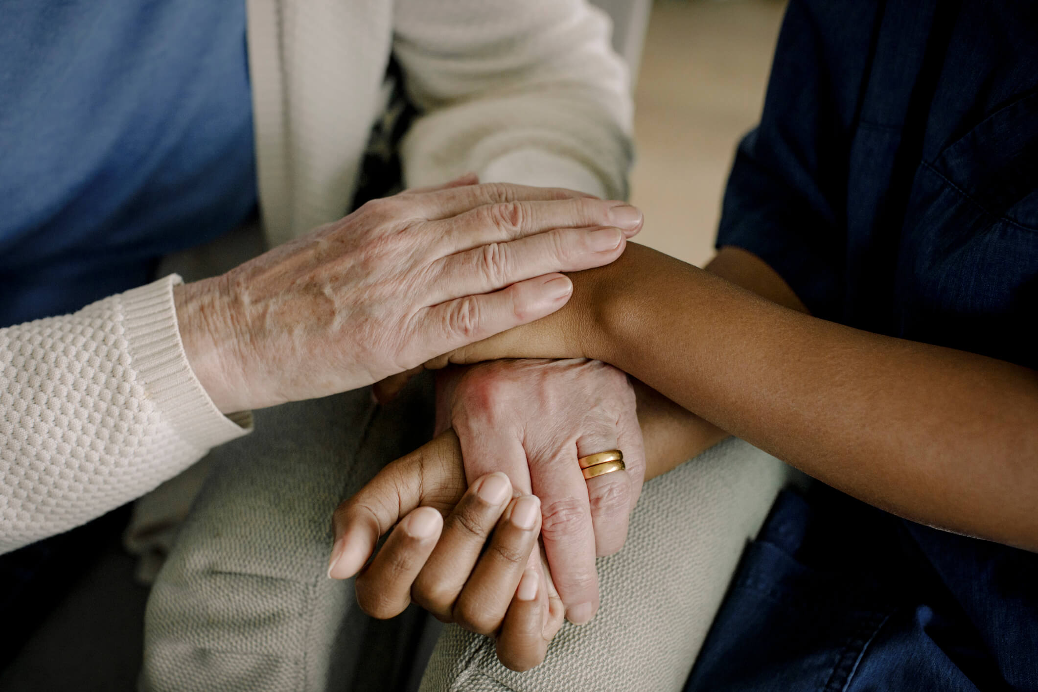 Midsection of senior woman and female healthcare worker with hands stacked at retirement home