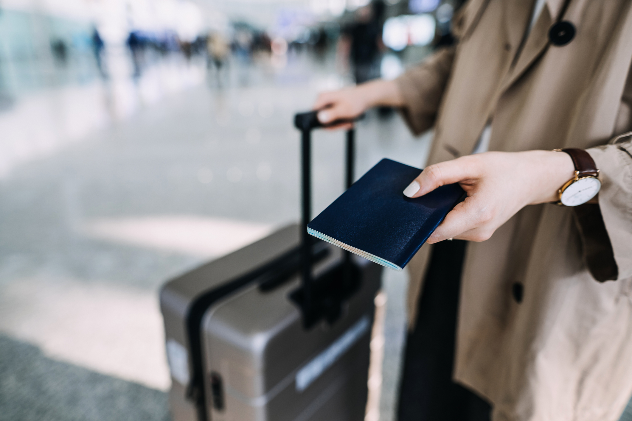 Cropped shot, mid-section of young woman carrying suitcase and holding passport at airport terminal. Ready to travel. Travel and vacation concept. Business person on business trip