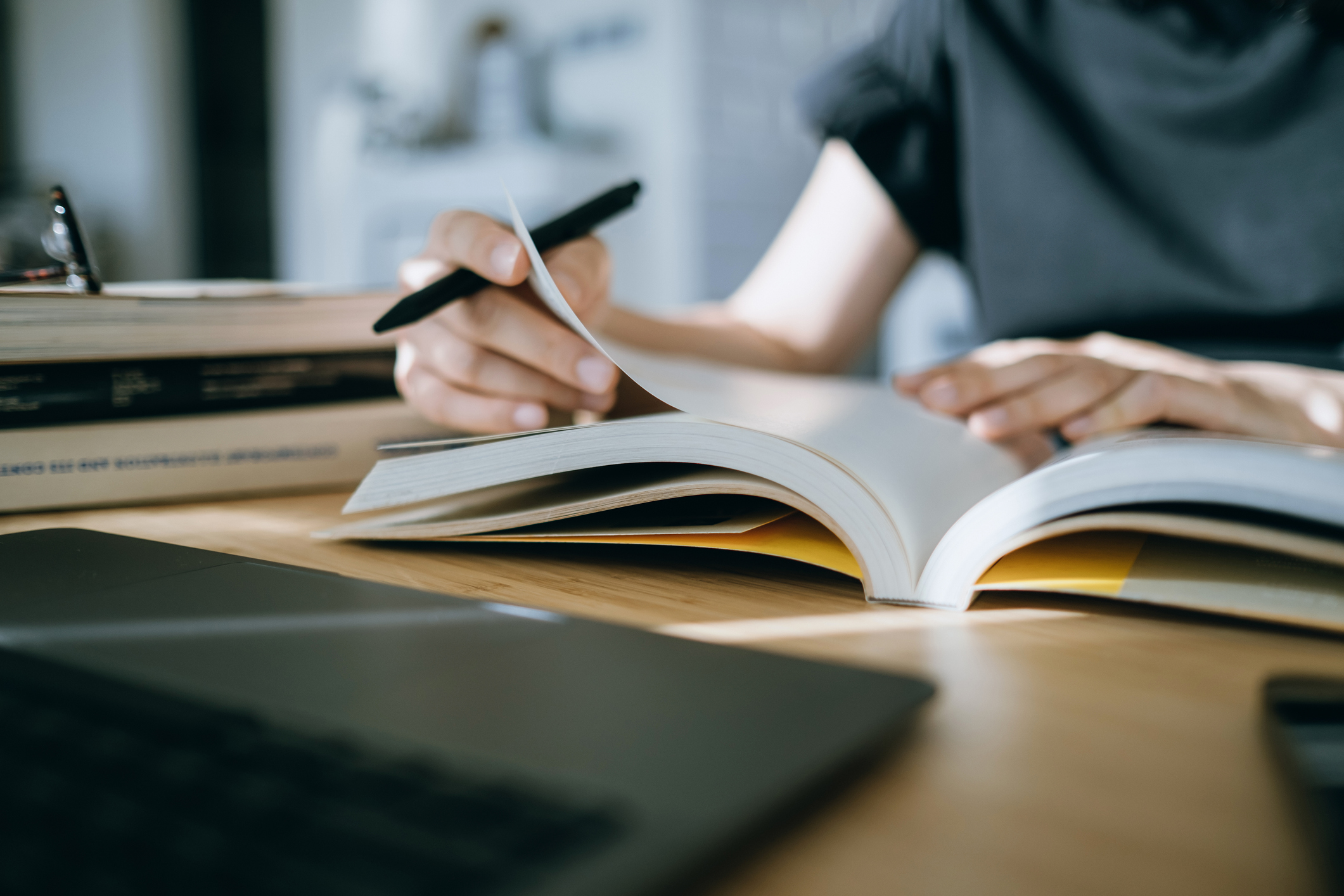 Close up. mid-section of young Asian woman reading book and making notes at home, concentrates on her studies. Further education concept