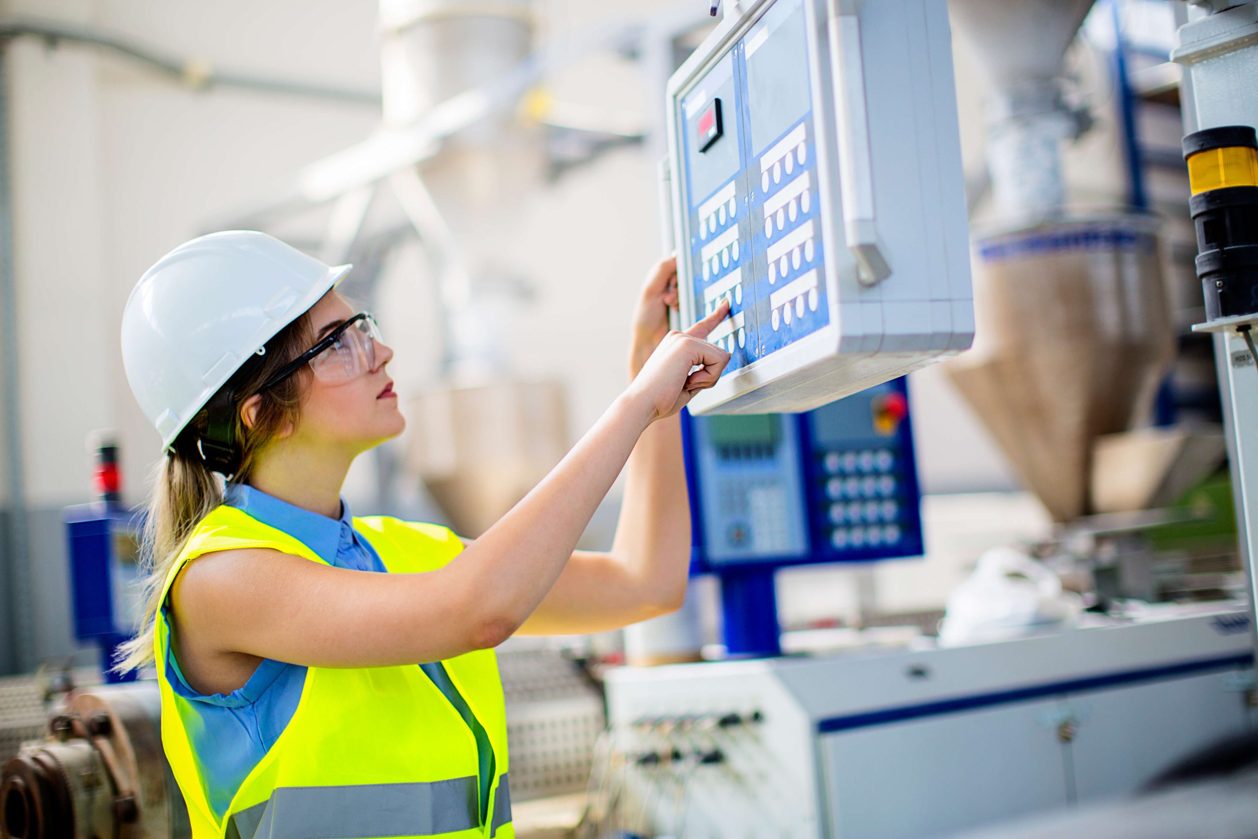 female worker in PPE operating an industrial control unit